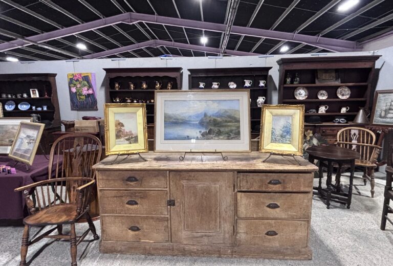image of the stand at the antique fair with pictures, sideboard and dressers behind.