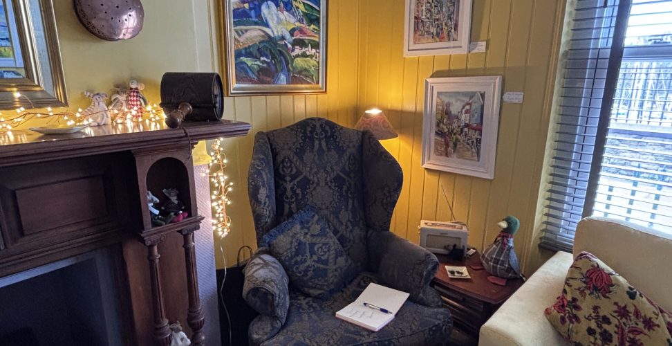 Large wing chair in the corner by the fireplace surrounded by original art